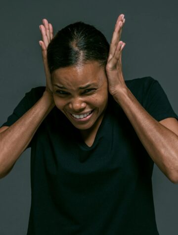 woman in black v neck t shirt covering ears